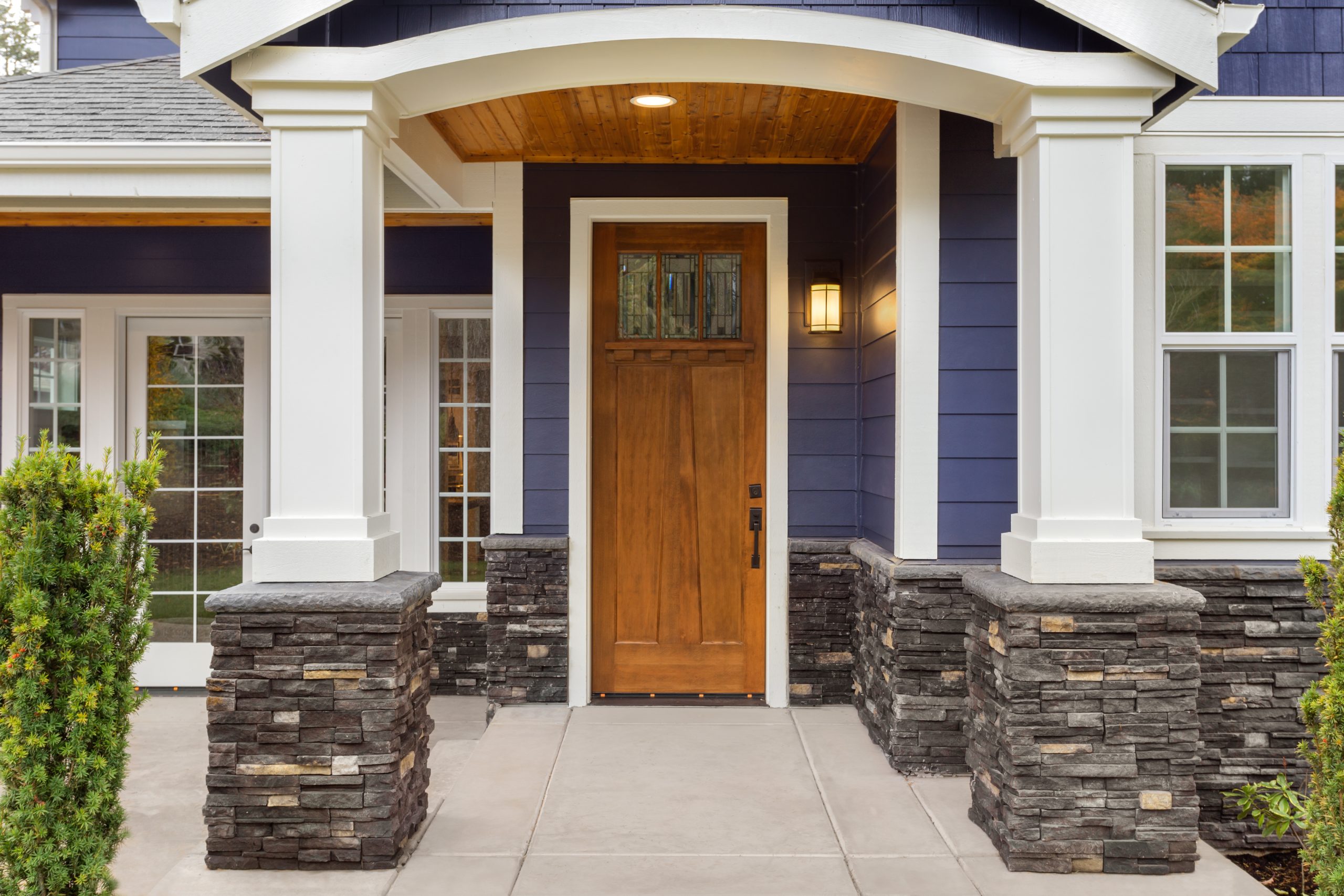 New Luxury Home Exterior Detail: New House Front Door and Covere Timber-frame covered porch addition with stone columns and cedar shake siding on an Okanagan home