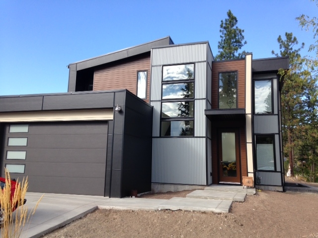 Hi-Lite Exteriors grey and wood modern exterior Modern Okanagan home with dark corrugated metal panel and wood-accent siding installed by Hi-Lite Exteriors